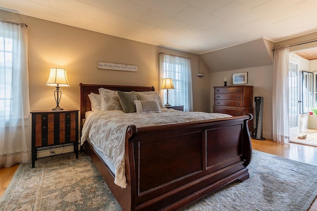 bedroom with wood-type flooring, lofted ceiling, and multiple windows