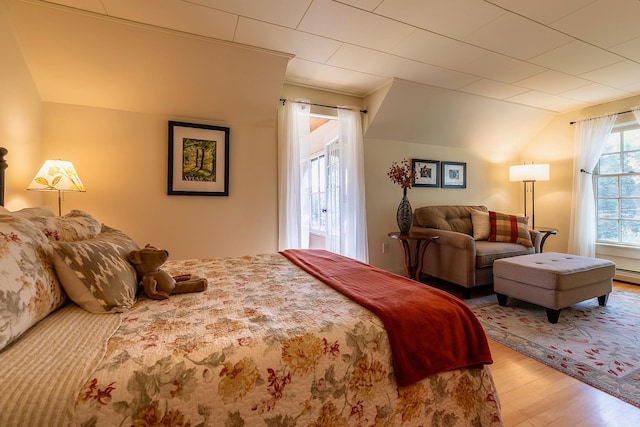 bedroom with light hardwood / wood-style flooring, baseboard heating, and vaulted ceiling