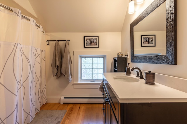 bathroom with lofted ceiling, baseboard heating, hardwood / wood-style flooring, and vanity