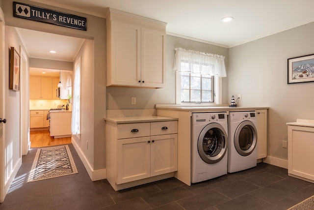 laundry room featuring ornamental molding, cabinets, dark tile patterned flooring, and washer and dryer