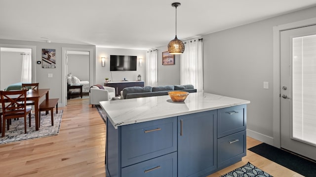 kitchen with pendant lighting, a kitchen island, blue cabinets, and light hardwood / wood-style flooring