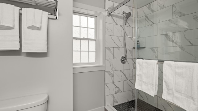 bathroom featuring toilet and a shower with shower door