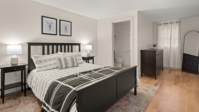 bedroom with connected bathroom, hardwood / wood-style floors, and a walk in closet