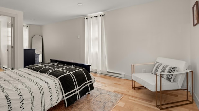 bedroom with hardwood / wood-style floors and a baseboard heating unit