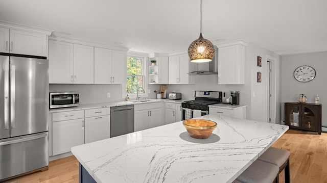 kitchen featuring light hardwood / wood-style floors, decorative light fixtures, sink, white cabinets, and appliances with stainless steel finishes