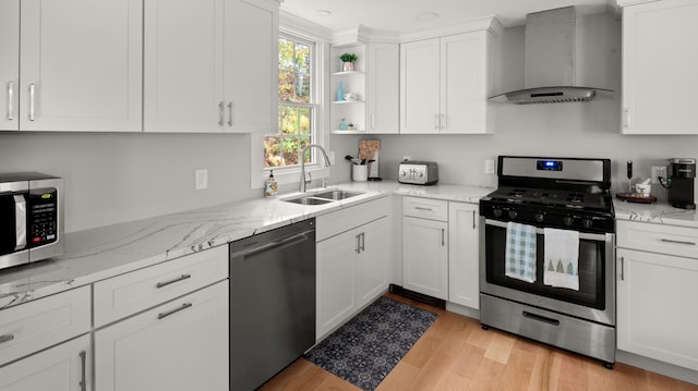 kitchen featuring white cabinets, sink, wall chimney exhaust hood, light hardwood / wood-style flooring, and stainless steel appliances