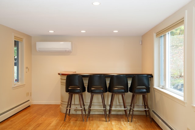 bar with a healthy amount of sunlight, a wall mounted air conditioner, and a baseboard radiator