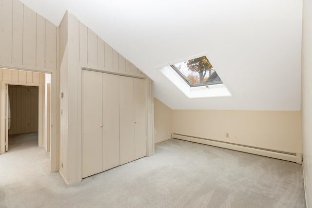 bonus room featuring light carpet, lofted ceiling with skylight, and a baseboard heating unit