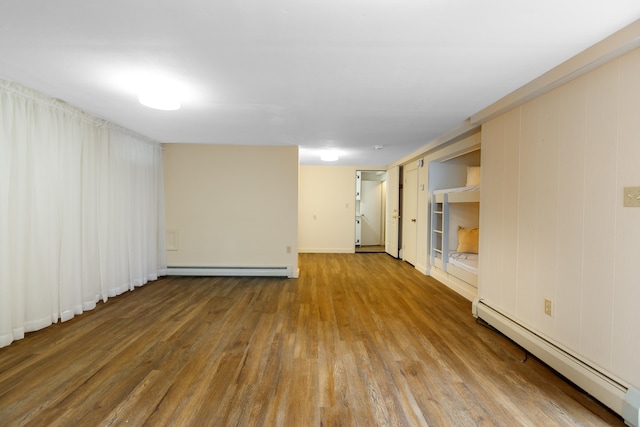 empty room with hardwood / wood-style flooring and a baseboard heating unit