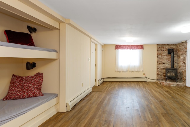 unfurnished living room featuring hardwood / wood-style floors and a baseboard heating unit