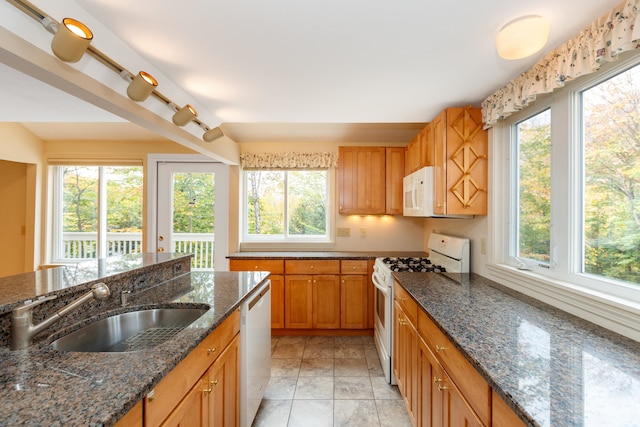 kitchen featuring white appliances, a wealth of natural light, and dark stone counters