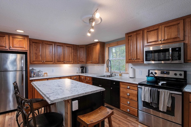 kitchen featuring light hardwood / wood-style floors, a kitchen breakfast bar, sink, appliances with stainless steel finishes, and a center island