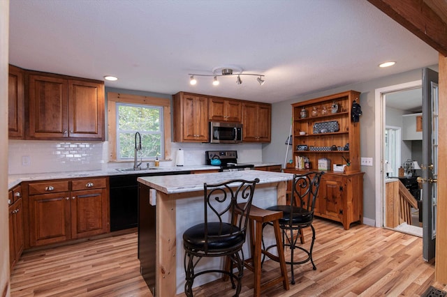 kitchen featuring black appliances, a center island, sink, and light hardwood / wood-style flooring