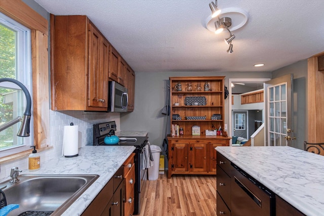 kitchen with tasteful backsplash, light hardwood / wood-style flooring, sink, black range with electric cooktop, and a textured ceiling