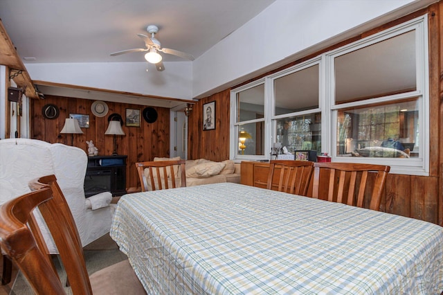 carpeted dining space with ceiling fan, lofted ceiling, and wood walls