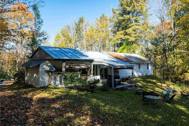 rear view of property featuring a fire pit and a lawn