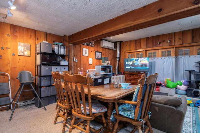 dining space with wood walls, light colored carpet, a wall unit AC, and a textured ceiling