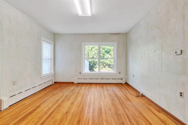 empty room with light wood-type flooring and a baseboard heating unit