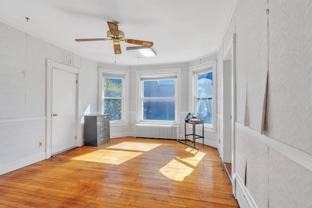 interior space with plenty of natural light, light wood-type flooring, radiator heating unit, and ornamental molding