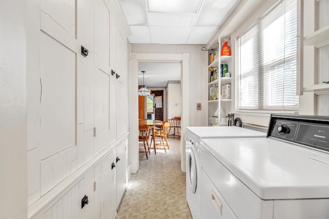 clothes washing area featuring washing machine and dryer and cabinets