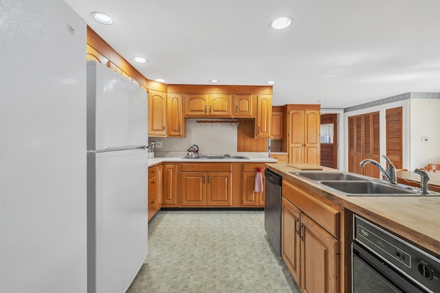 kitchen with gas stovetop, sink, white refrigerator, dishwasher, and black dishwasher