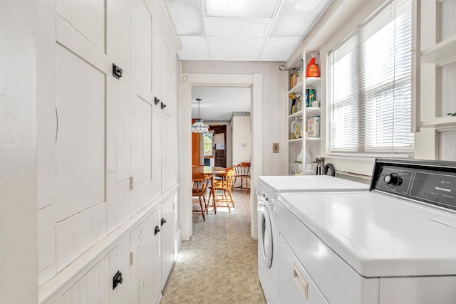 clothes washing area with cabinets and washing machine and clothes dryer