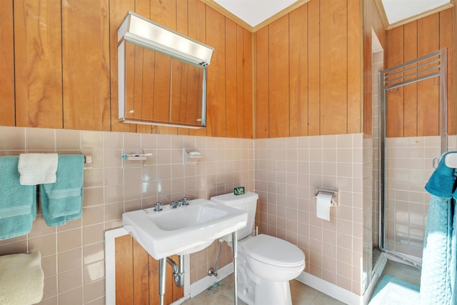 bathroom featuring tile patterned floors, sink, wooden walls, toilet, and tile walls