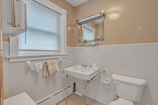 bathroom with tile patterned flooring, a baseboard radiator, tile walls, and toilet