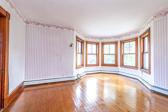 unfurnished room with wallpapered walls and hardwood / wood-style flooring