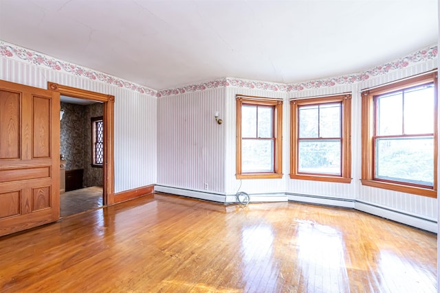empty room featuring hardwood / wood-style flooring and wallpapered walls