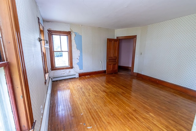 spare room with a baseboard heating unit, light wood-style floors, and wallpapered walls
