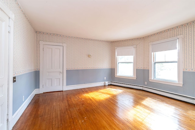spare room with wainscoting, a baseboard radiator, hardwood / wood-style floors, and wallpapered walls
