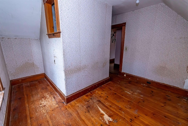 additional living space with hardwood / wood-style flooring, baseboards, and vaulted ceiling