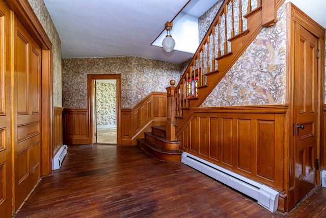 stairs featuring a baseboard heating unit, wallpapered walls, baseboard heating, and wainscoting
