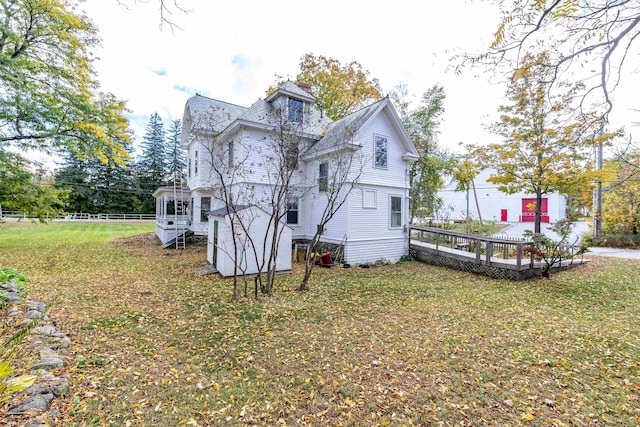 back of house featuring a wooden deck, a lawn, and fence