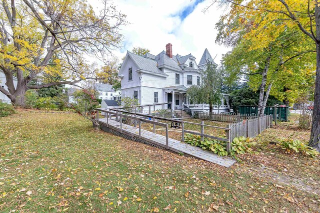 view of side of property featuring fence private yard, a lawn, and a chimney