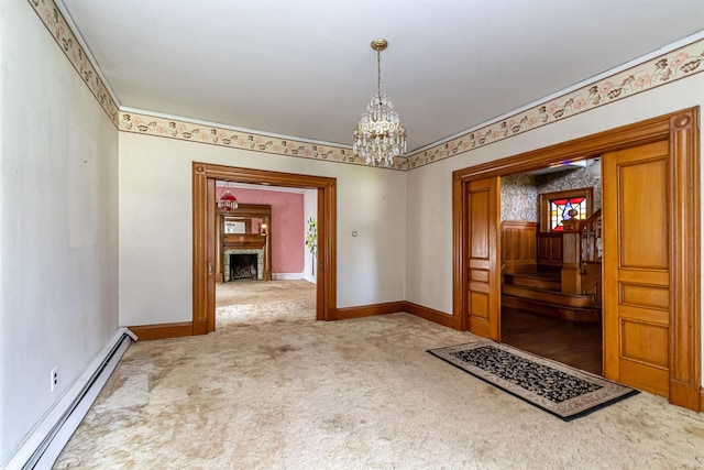 carpeted spare room with a baseboard heating unit, baseboards, an inviting chandelier, and a fireplace