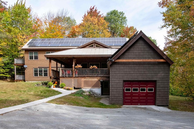 view of front of house with a front yard, a garage, solar panels, and a porch