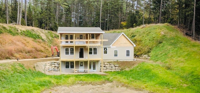 rear view of house featuring a patio area, a balcony, french doors, and a forest view