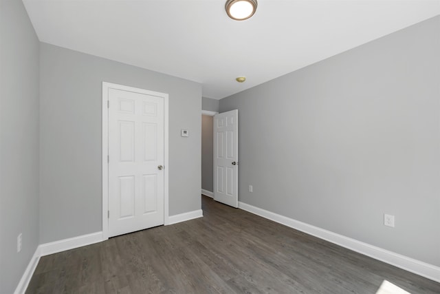 unfurnished bedroom with dark wood finished floors and baseboards