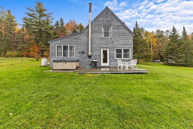 rear view of property featuring a yard, a wooden deck, and a hot tub