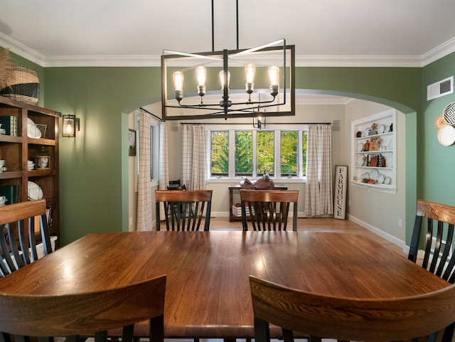 dining space with a chandelier, light wood-type flooring, and ornamental molding