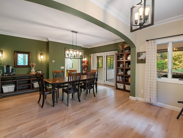 dining area with french doors, light hardwood / wood-style flooring, crown molding, and a notable chandelier