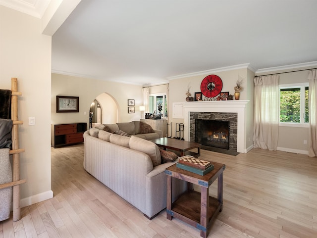 living room featuring a stone fireplace, crown molding, and light hardwood / wood-style flooring