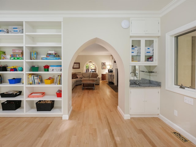 corridor featuring sink, crown molding, and light hardwood / wood-style flooring