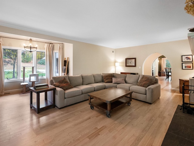 living room featuring light hardwood / wood-style flooring, ornamental molding, and a notable chandelier