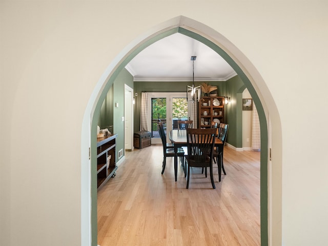 dining room with light wood-type flooring, crown molding, and an inviting chandelier