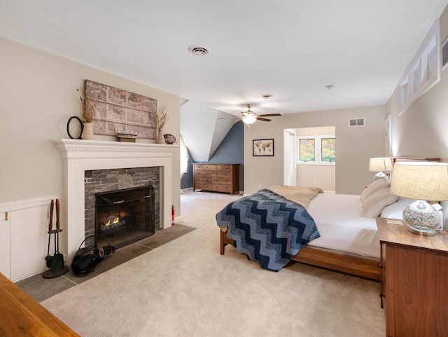 bedroom with ceiling fan, a fireplace, and light carpet