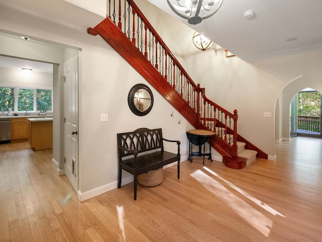 staircase with wood-type flooring, crown molding, and a chandelier