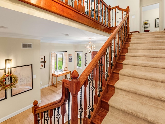 stairs with a chandelier, hardwood / wood-style flooring, and ornamental molding